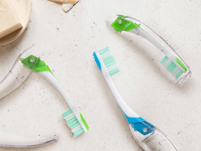 GUM Travel toothbrush in two colours: the blue one lying flat and the green one folded