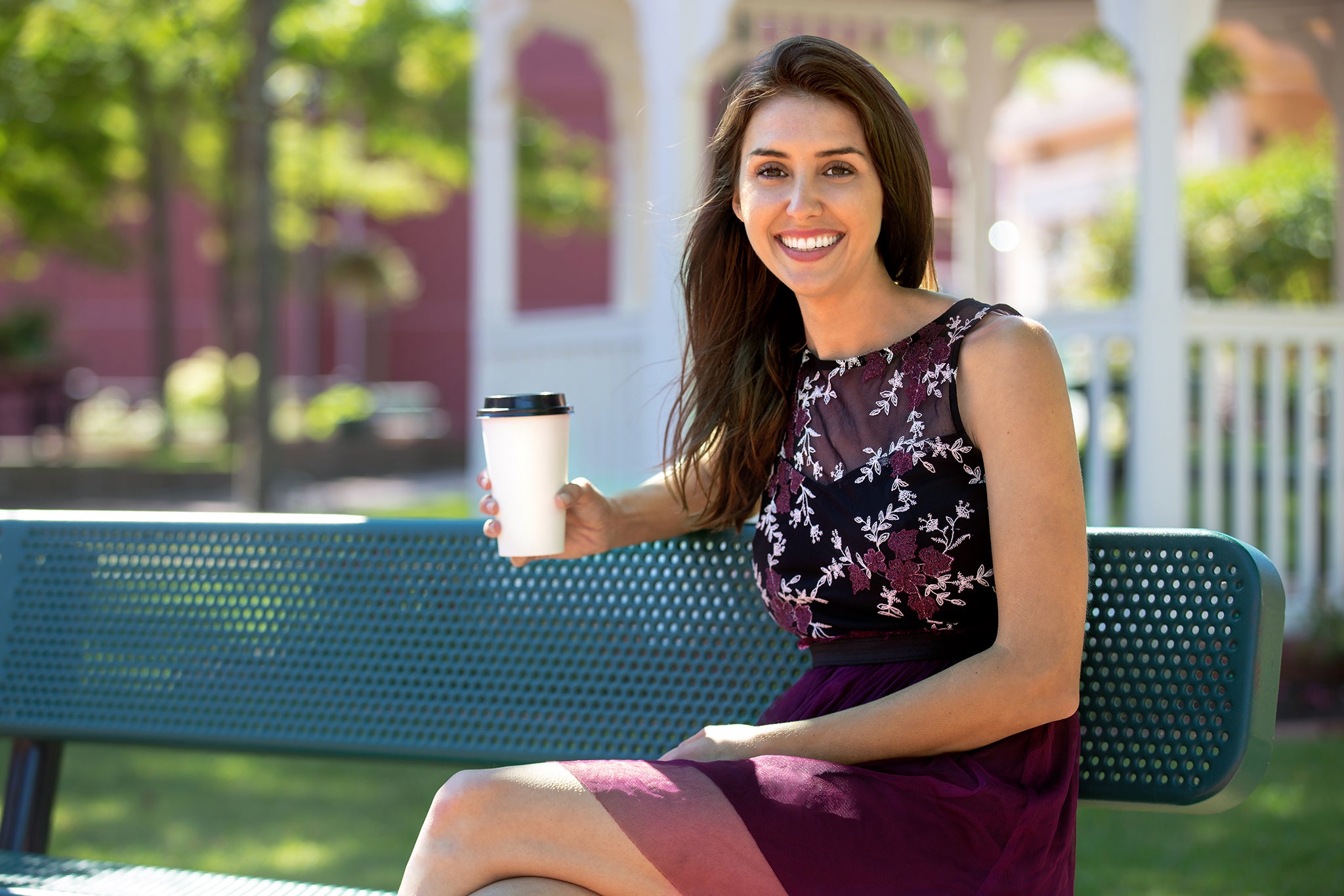 Woman holding a cup outside on a bench